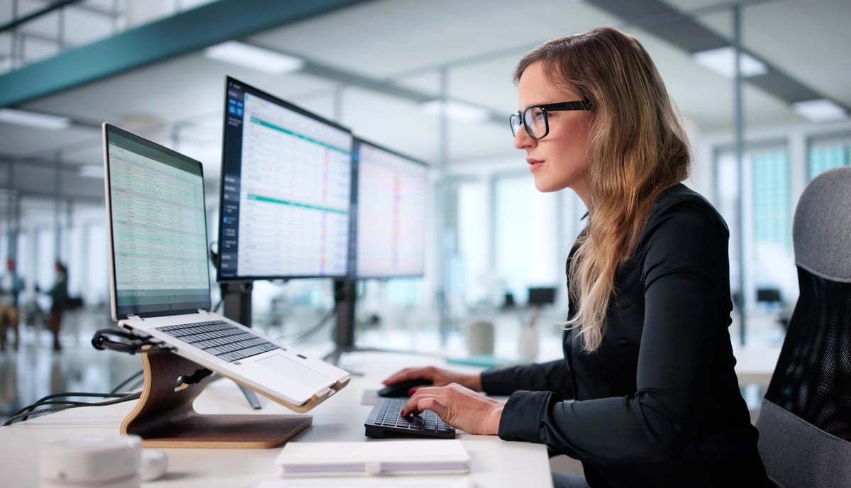Woman in office analyzing financial reports on spreadsheet, focused on accuracy and data review